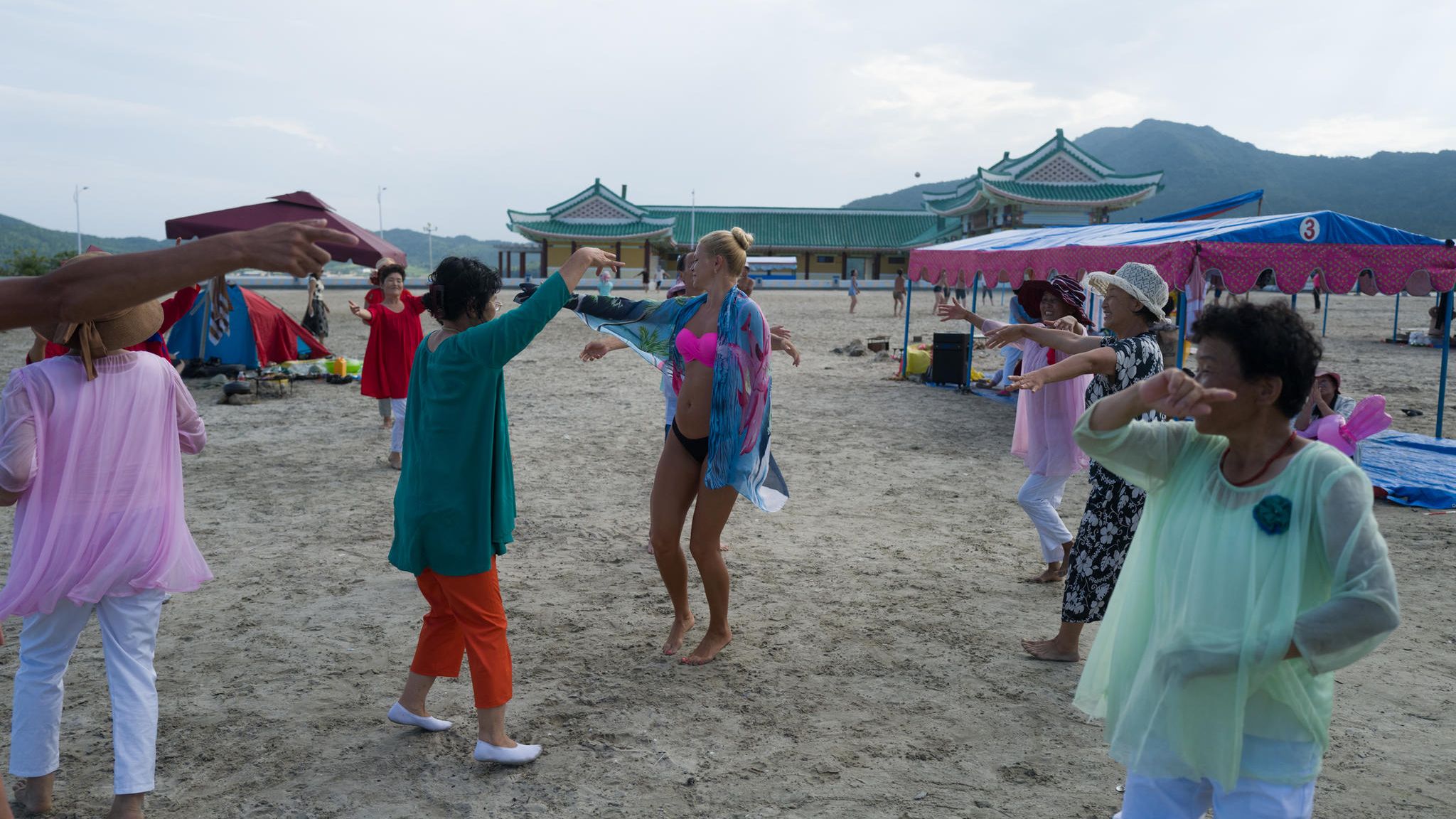 Nordkoreanerinnen laden die Touristinnen aus Russland zum Tanz. Die Reisegruppe ist entweder gemeinsam am Strand - oder im Hotel. Die Zelte sollen vor der Sonne schützen, koreanische Sommer sind heiß und schwül