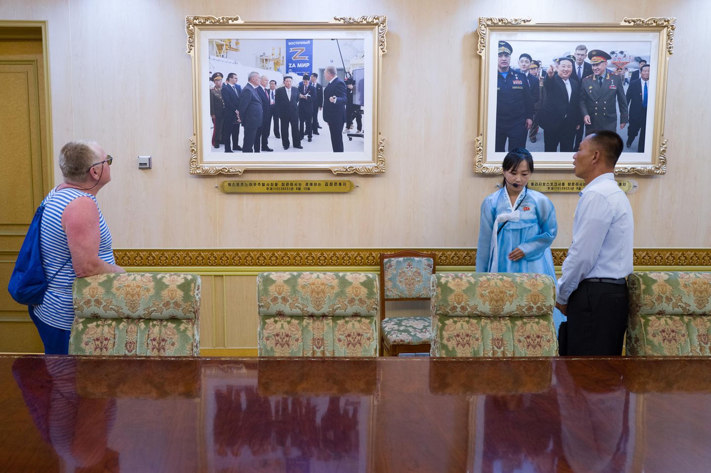 Eine Frau begutachtet zwei an der Wand hängende Fotos von Kim Jong-un Eine Frau begutachtet zwei an der Wand hängende Fotos von Kim Jong-un