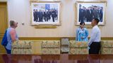 Eine Frau begutachtet zwei an der Wand hängende Fotos von Kim Jong-un