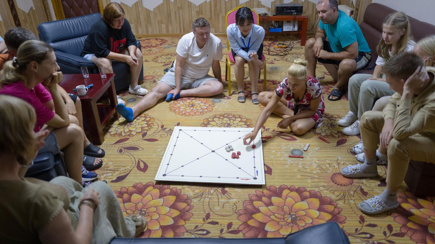 Russen sitzen auf dem Boden und spielen ein Brettspiel Russen sitzen auf dem Boden und spielen ein Brettspiel