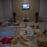 Menschen vliegen auf dem Boden, im Hintergrund läuft ein Fernseher