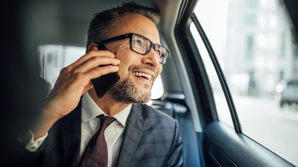 Mit dem Vodafone Business-Tarif von unterwegs arbeiten: Mann sitzt im Auto und telefoniert mit dem Handy.