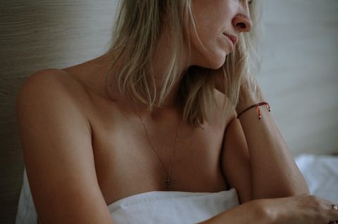 Frau mit Kinderwunsch blickt traurig auf das Bett neben sich