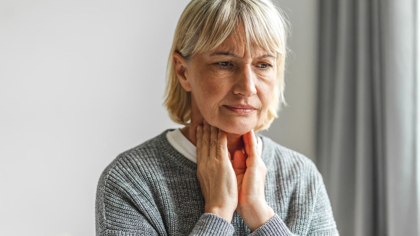 Frau fasst sich an den Hals Frau fasst sich an den Hals