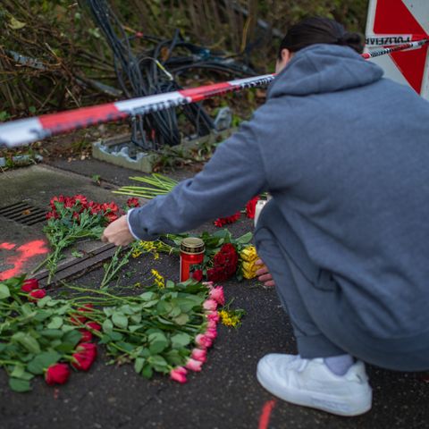 Eine Frau legt Blumen an der Unfallstelle in Esslingen am Neckar nieder