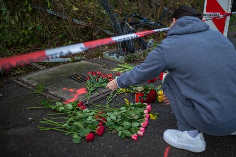 Eine Frau legt Blumen an der Unfallstelle in Esslingen am Neckar nieder