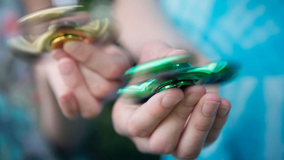 Zwei Hände mit Fidget Spinnern in der Hand