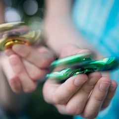 Zwei Hände mit Fidget Spinnern in der Hand