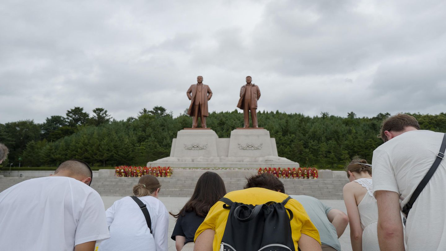 Sich verbeugende Touristen vor 2 Statuen in Nordkorea