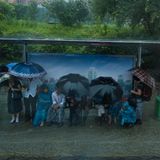 Menschen warten im Regen auf den Bus