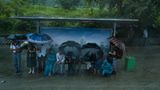 Menschen warten im Regen auf den Bus
