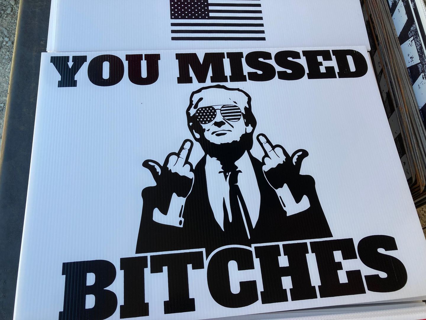 Knapp daneben Wahlkampfschild mit stinkefingerzeigendem Trump
