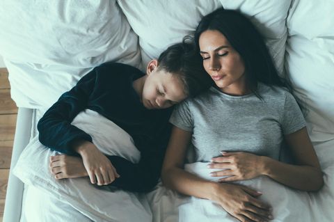 Zeitumstellung: Eine Mutter liegt mit ihrem Sohn im Bett und schläft