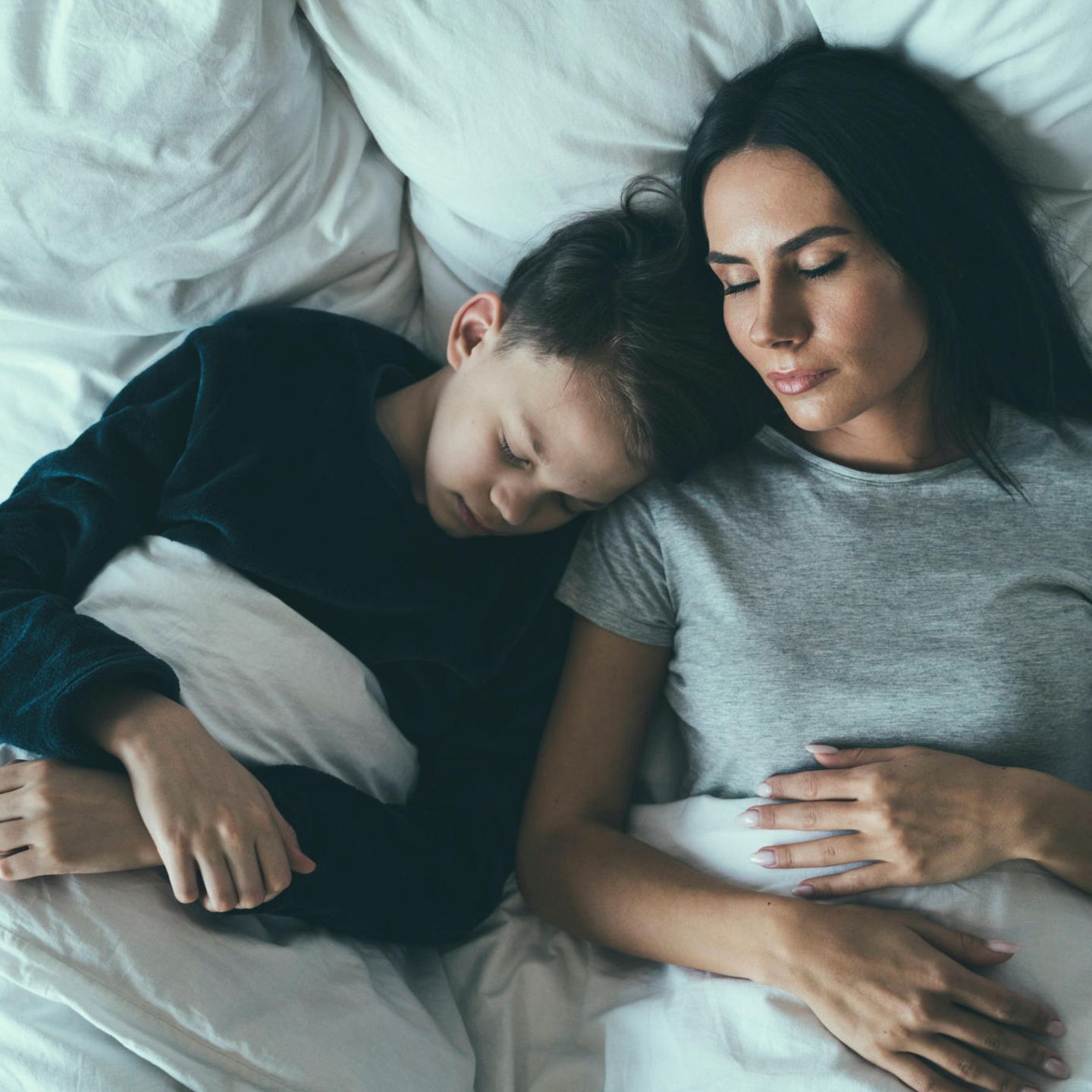 Zeitumstellung: Eine Mutter liegt mit ihrem Sohn im Bett und schläft