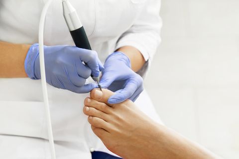Fußpflegerin behandelt den Fuß eines Patienten