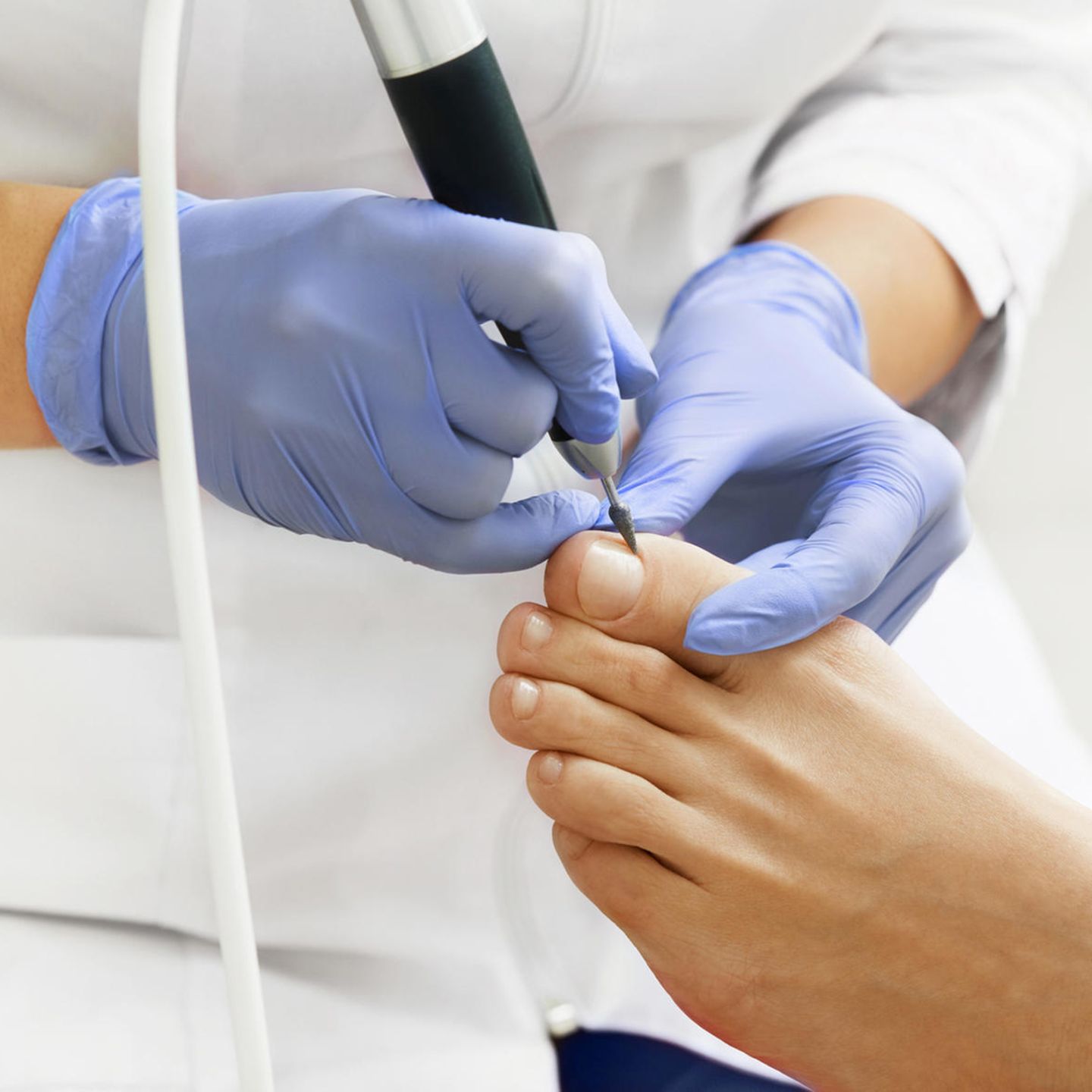 Fußpflegerin behandelt den Fuß eines Patienten