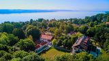 Hinter hohen Bäumen in der Nähe des Ufers liegt das Internat Landheim Ammersee.