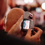 Ein Mann filmt einen nahen, intimen Auschnitt einer Darstellerin der Erotikmesse Venus mit einer kleinen Kamera