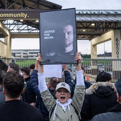 Demonstranten vor der Airbase halten Schilder hoch