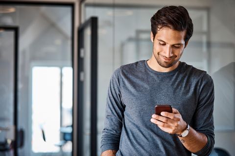 Flexible Handy-Tarife für Geschäftskunden: Mann schaut auf sein Smartphone und lächelt.