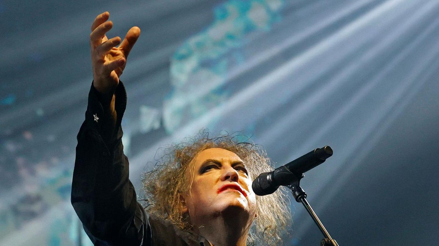 Robert Smith von The Cure reckt auf der Bühne den Arm in die Höhe