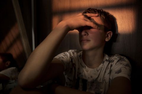 Gedanken an Suizid? Junger Mann hält sich verzweifelt die Hand vor die Augen