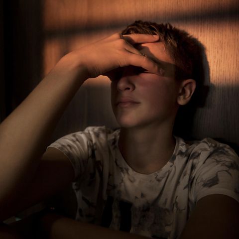 Gedanken an Suizid? Junger Mann hält sich verzweifelt die Hand vor die Augen