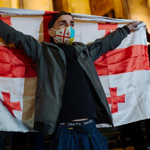 Georgia: A demonstrator raises the Georgian flag