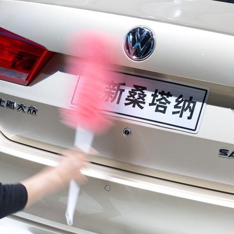 A woman cleans the rear of a VW Santana
