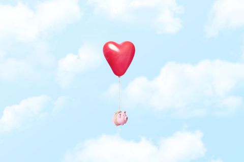 Symbolbild Finanzen in der Beziehung: Ein Sparschwein schwebt im Himmel, es ist an einen Herz-Luftballon gebunden