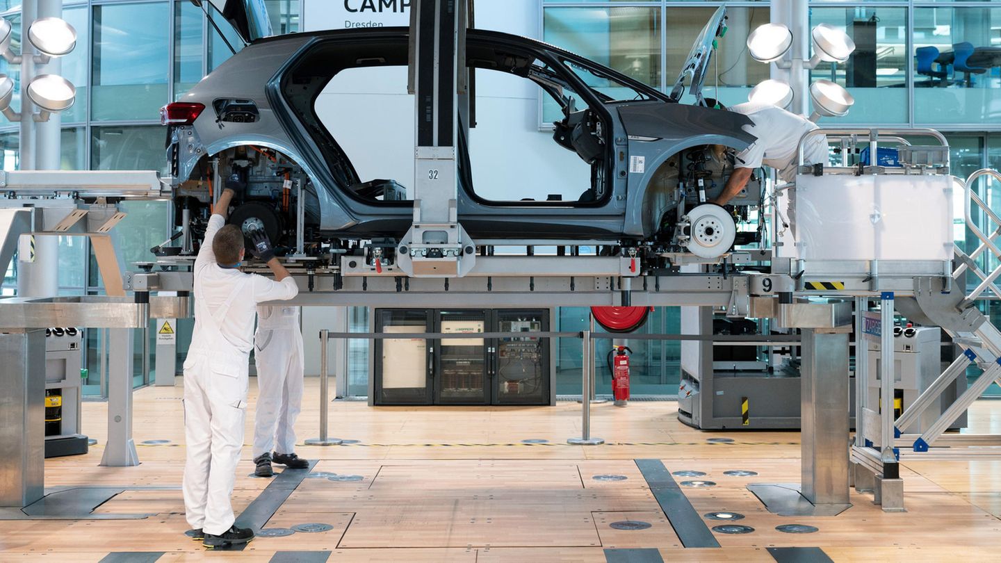 Im VW-Werk Dresden montieren weiß gekleidete Arbeiter ein E-Auto vom Typ i.D3
