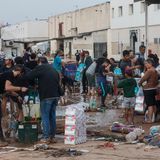 Anwohner suchen nach Grundbedarfsartikeln in einer von Schlamm bedeckten Straße