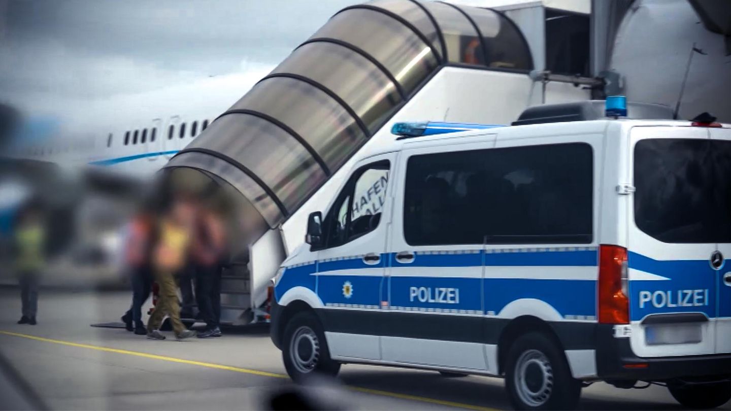 Die Passagiere werden von Polizisten in das Flugzeug begleitet