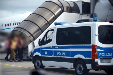 Die Passagiere werden von Polizisten in das Flugzeug begleitet