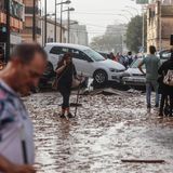 Menschen laufen durch das überflutete Valencia, Autos stapeln sich