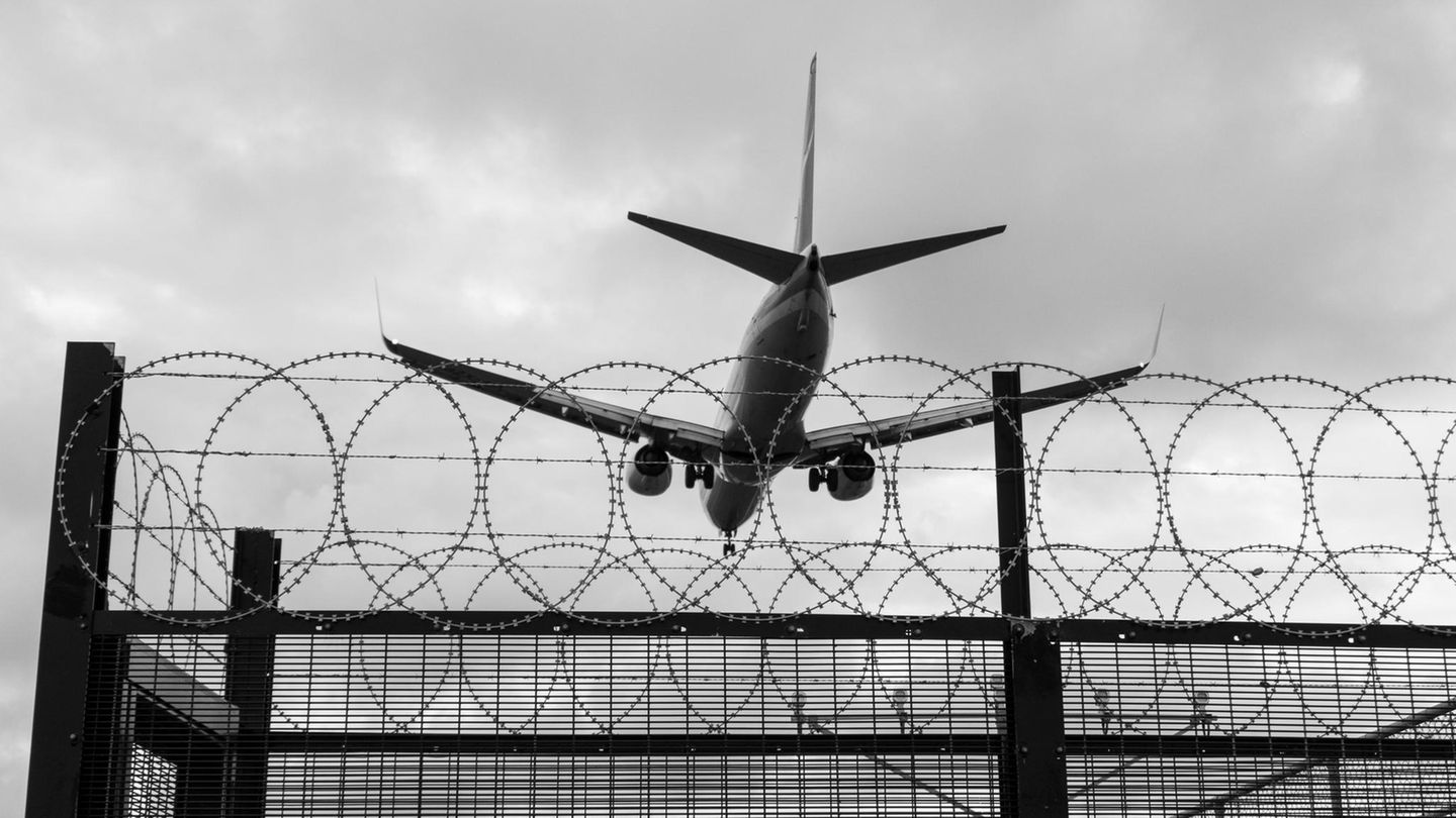 Abschiebung (Symbolbild): Ein Flugzeug fliegt über Stacheldraht