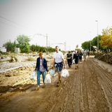 Menschen tragen Lebensmittel in einem von den Fluten betroffenen Gebieten
