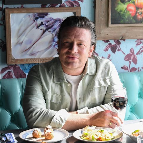 Portrait Jamie Oliver in einem Restaurant mit unterschiedlichen speisen auf dem Tisch