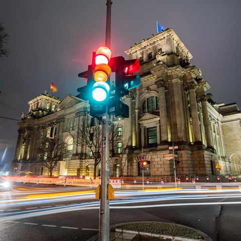 Eine Ampel in der Dunkelheit vor dem Reichstagsgebäude in Berlin
