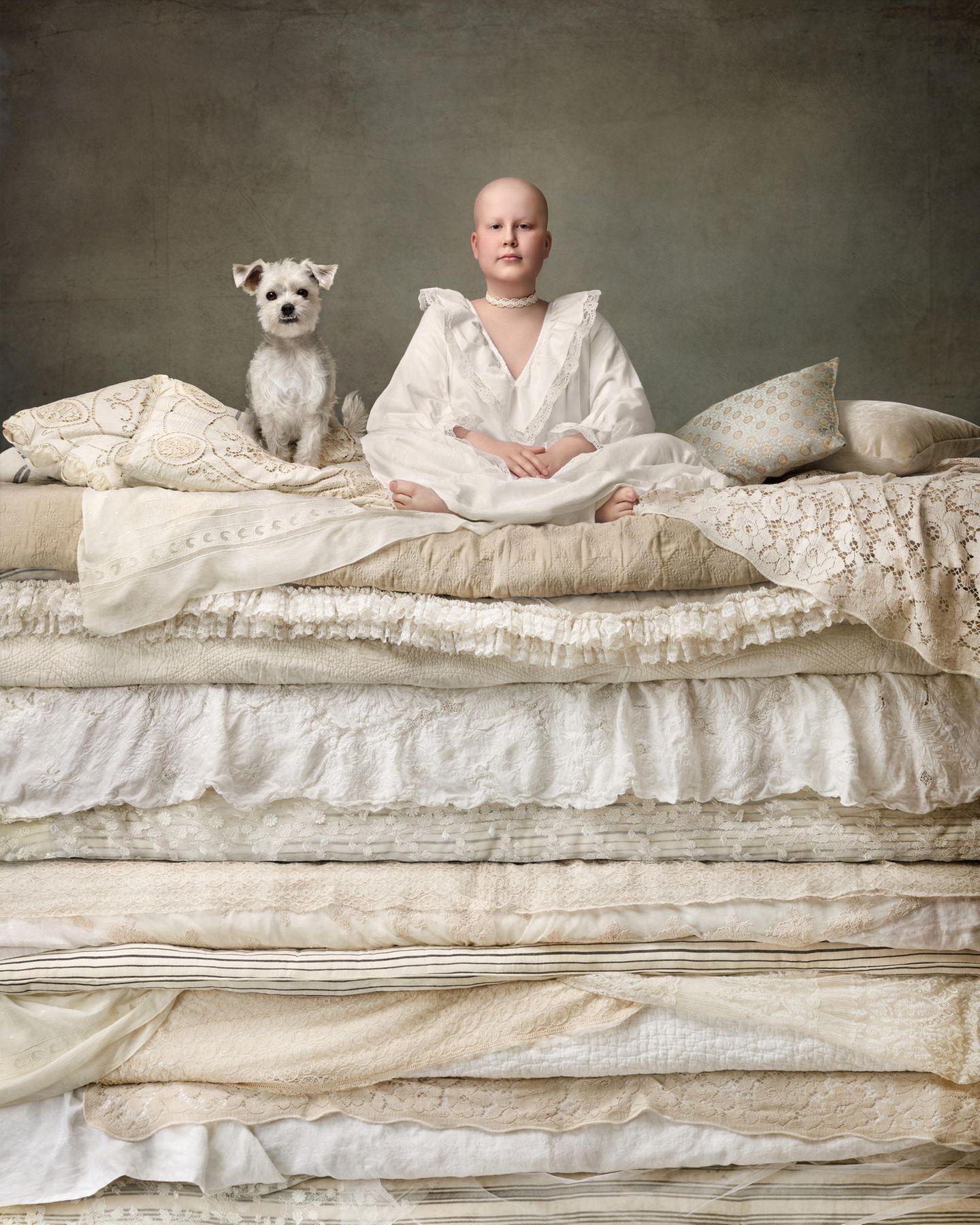 Prinzessin und Hund auf der Erbse Ein Mädchen mit einer Glatze sitzt mit ihrem kleinen Hund auf einem Matratzenberg