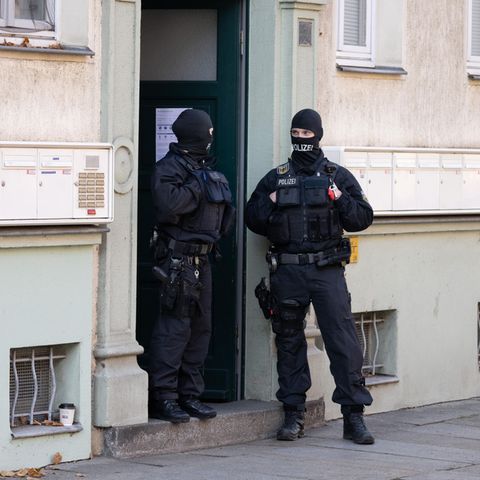 Polizisten stehen während einer Razzia gegen mutmaßliche Rechtsextreme in einem Hauseingang im Dresdner Stadtteil Cotta