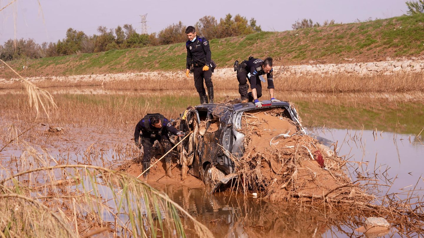 Polizisten suchen in einem kaputten Auto nach Überlebenden der Flutkatastrophe