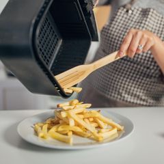 Hispanoamerikanerin macht Pommes frites in der Heißluftfritteuse
