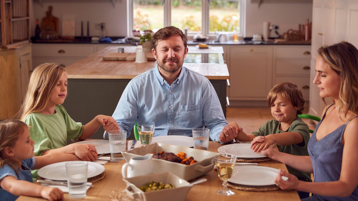 Eine Familie betet am Tisch