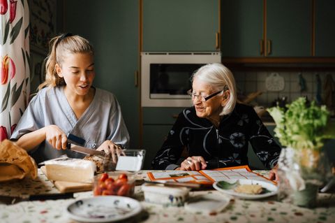 Eine Pflegekraft schneidet Brot für eine alte Dame