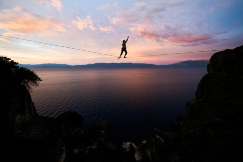 Instabilität (Symbolfoto) Ein Mensch balanciert auf einer Slackline, unter ihm eine Bergschlucht