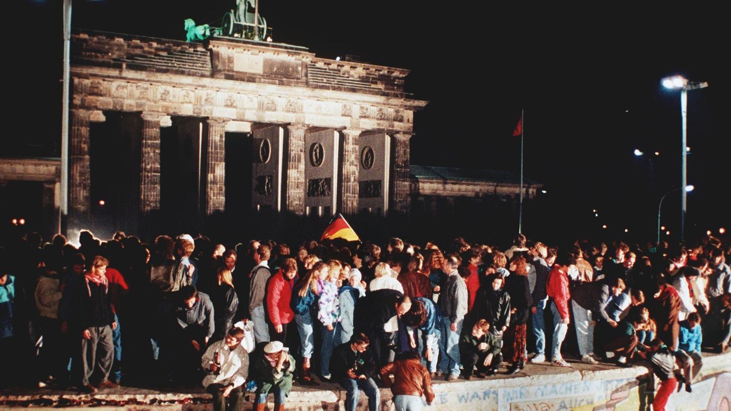 9. November 1989: Menschen stehen auf der Berliner Mauer am Abend des Mauerfalls