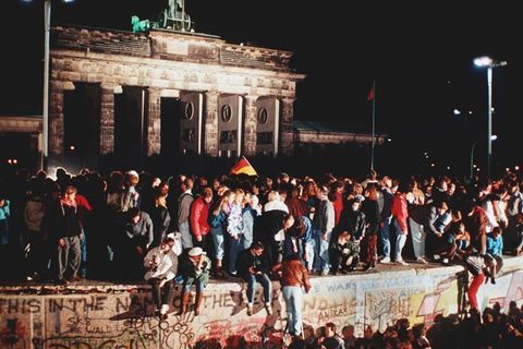 Menschen stehen auf der Berliner Mauer am Abend des Mauerfalls