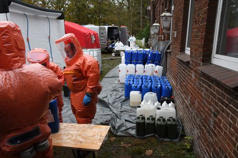 Polizisten in Schutzanzügen holen große Mengen Chemikalien in Kanistern aus einem Drogenlabor