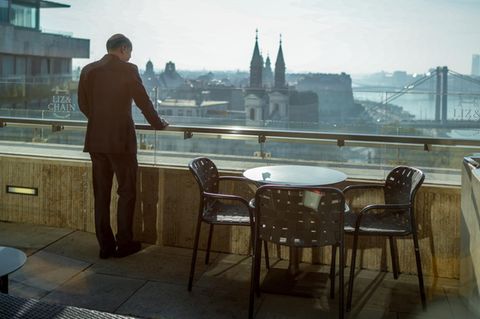 Olaf Scholz steht auf einem Balkon und schaut auf Budapest